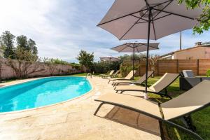 a swimming pool with lounge chairs and an umbrella at Maison proche Vaison la Romaine in Saint-Romain-en-Viennois