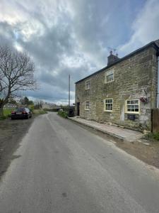 an empty road next to an old stone building at Delightful detached 2 bedroom cottage in Grantley