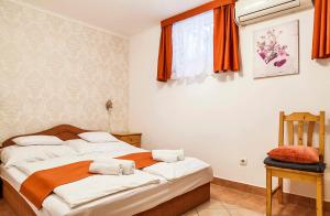 a bedroom with two beds with orange curtains and a chair at Apartman Levendula in Balatonfüred
