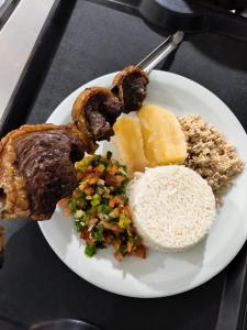 a white plate of food with rice and meat at Criptos Hotel e Restaurante in Várzea Grande
