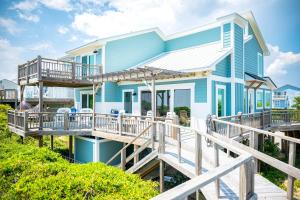 a blue house with a porch and a deck at Beach Buzz by Oak Island Accommodations in Caswell Beach