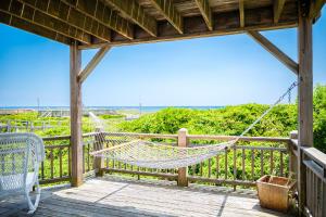 a hammock on a porch with a view of the ocean at Beach Buzz by Oak Island Accommodations in Caswell Beach