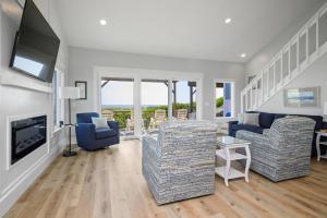 a living room with two chairs and a television at Beach Buzz by Oak Island Accommodations in Caswell Beach +98 photos