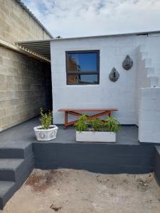 a picnic table on a patio with two potted plants at Cozy Corner Serenity Suite in Bredasdorp