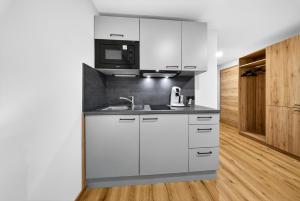 a white kitchen with a sink and a microwave at Schinagl Klaus in Klaus an der Pyhrnbahn