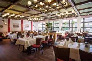 a restaurant with white tables and chairs and windows at Hotel-Restaurant Dechbettener Hof in Regensburg