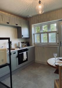 a kitchen with a stove and a table and windows at Guest house in Compton in Winchester