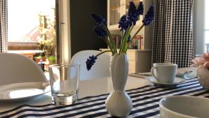 a white vase with purple flowers in it on a table at Erholung und Wellness in Dänschendorf +15 photos