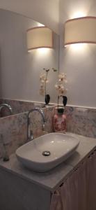a bathroom sink with two lights and flowers in a vase at Casa Tulliola in Moneglia +30 photos