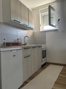 a kitchen with white cabinets and a sink and a window at Apartman Davidovic in Divčibare