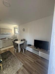 a living room with a table with chairs and a television at Apartman Davidovic in Divčibare