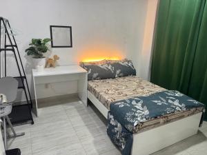 a bedroom with a bed and a desk and green curtains at Home Transit Hulhumale' Phase 2 in Male City