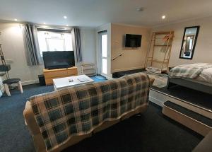 a living room with a couch and a bed and a television at The Glenerne in Eyemouth