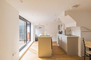 a kitchen with white cabinets and a large window at Crafters Cottage in Sandwich