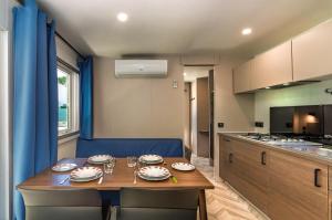 a kitchen with a wooden table and blue chairs and a kitchen with a table at Campeggio La Quiete in Marina di Massa +68 photos