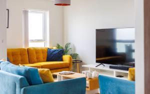 a living room with a yellow couch and a flat screen tv at Colonels Rest - Luxury Beachside Townhouse with Sea Views in Sandown, Sleeps 10 in Sandown +91 photos