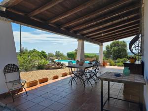 a patio with a table and chairs and a pool at Villa Altora in Nuragheddu