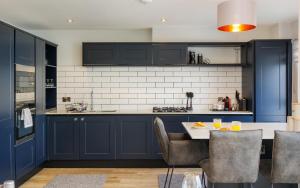 a kitchen with blue cabinets and a table with chairs at Colonels Rest - Luxury Beachside Townhouse with Sea Views in Sandown, Sleeps 10 in Sandown