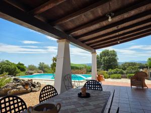 a patio with a table and chairs and a swimming pool at Villa Altora in Nuragheddu +39 photos