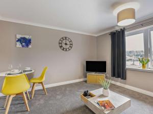 a living room with a yellow chair and a tv at 1 Bed in Oban oc-96079 in Oban