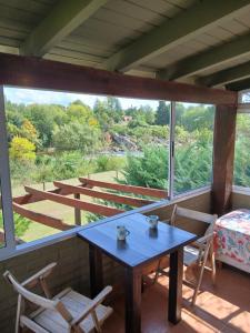 a table and chairs on a porch with a view at Miralrio in Santa Rosa de Calamuchita