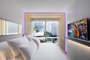 a bedroom with a large white bed with a window at YOTEL Bangkok Sukhumvit in Ban Nong Chaeng
