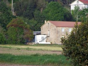 a large brick building with a garage in a field at Brisa do Mar in Laxe