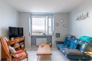 a living room with a blue couch and a tv at La Rose des Sables in Tréffiagat