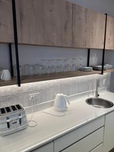 a white kitchen counter with a sink and glasses on a shelf at Duplex in Vainona in Harare +56 photos