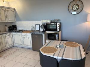 a kitchen with white cabinets and a table in it at La Rose des Sables in Tréffiagat +40 photos