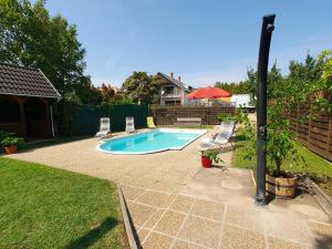 a swimming pool in a yard with chairs and a house at Apartment Anikó Nr 7 in Vonyarcvashegy