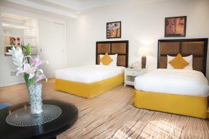 a hotel room with two beds and a vase of flowers at Plaza Inn Hotel in Doha