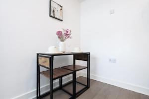 a black shelf with a vase of flowers on it at Studio - Kitchen - Parking - Ideal for Contractors in Swansea