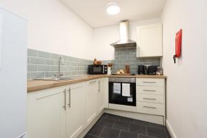 a kitchen with white cabinets and a sink at Studio - Kitchen - Parking - Ideal for Contractors in Swansea +22 photos