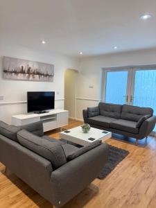 a living room with two couches and a flat screen tv at Windsor side in Datchet +4 photos