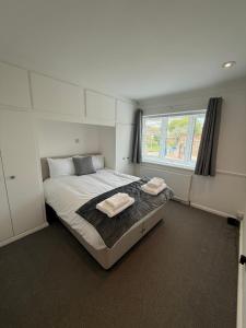 a bedroom with a large bed with two towels on it at Windsor side in Datchet