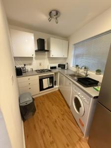 a kitchen with white cabinets and a sink and a dishwasher at Windsor side in Datchet