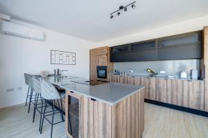 a kitchen with a counter and a bar with stools at Superlative 3BR Penthouse, Private Pool and Views in Hal Ghaxiak