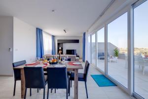 a dining room with a table and chairs and a large window at Superlative 3BR Penthouse, Private Pool and Views in Hal Ghaxiak +58 photos