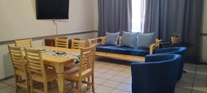 a dining room with a table and a blue couch at AMBROZIA Apartment-self catering-2bed2bath in Bloemfontein