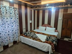 a bedroom with a bed and a curtain at BAKSHI lodge in Pahalgām