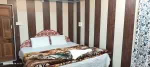 a bed with a chair in a room at BAKSHI lodge in Pahalgām +4 photos