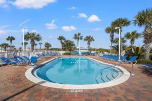 a swimming pool with blue chairs and palm trees at A-110, Pinnacle Port in Panama City Beach