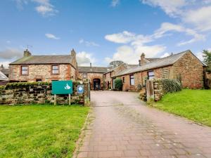 an old stone house with a sign in front of it at 1 Bed in Penrith oc-90416 in Kirkoswald