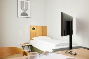 a bedroom with a bed and a desk with a tv at appartello - smarttime living Berlin in Berlin