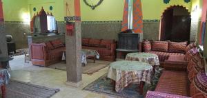 a living room with couches and tables and a stove at Écolodge OASIS Vallée du ZIZ Gîte DAR UL in Maarka