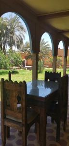 a wooden table and chairs on a porch at Écolodge OASIS Vallée du ZIZ Gîte DAR UL in Maarka