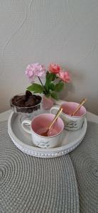 a tray with three bowls and flowers on a table at Rohu Apartment in Pärnu