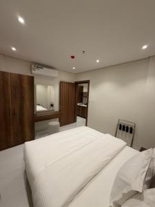 a bedroom with a large white bed and a bathroom at توليب حتا 2 Tulip Hatta in Al Khobar