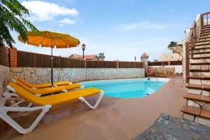 a pair of chairs and an umbrella next to a swimming pool at Las Casitas 28 in Corralejo